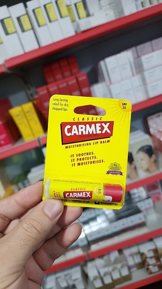 Carmex Classic Lip Balm SPF 15 in bright yellow packaging with red Carmex logo, tube visible on shelf.